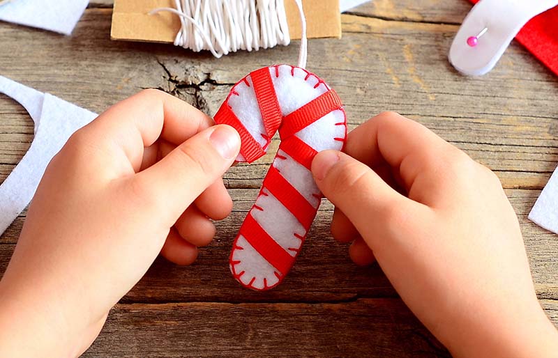 child holds christmas felt candy cane | christmas ornaments to sew