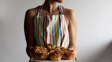 woman holding tray with breads | 20 Apron Pattern Projects to Get Crazy in the Kitchen With | Featured