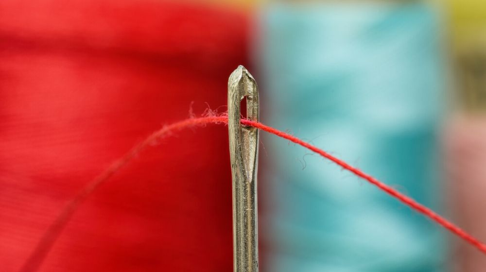 closeup shot of thread inside a needle | How to Sew By Hand In 6 Easy Steps