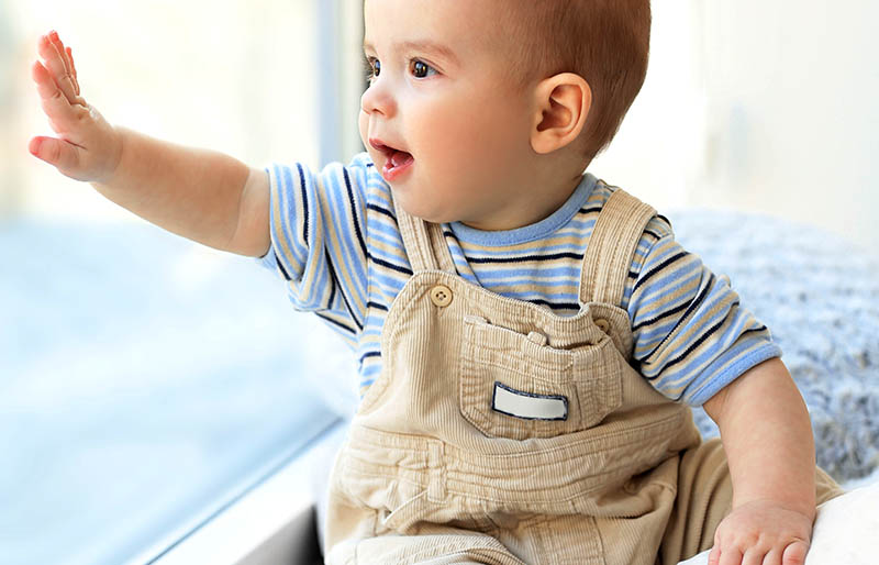 little baby boy looking out window | winter clothes for newborn