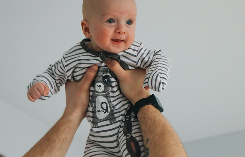 man in white tshirt carrying baby in black and white stripe onesie | winter clothes for newborn
