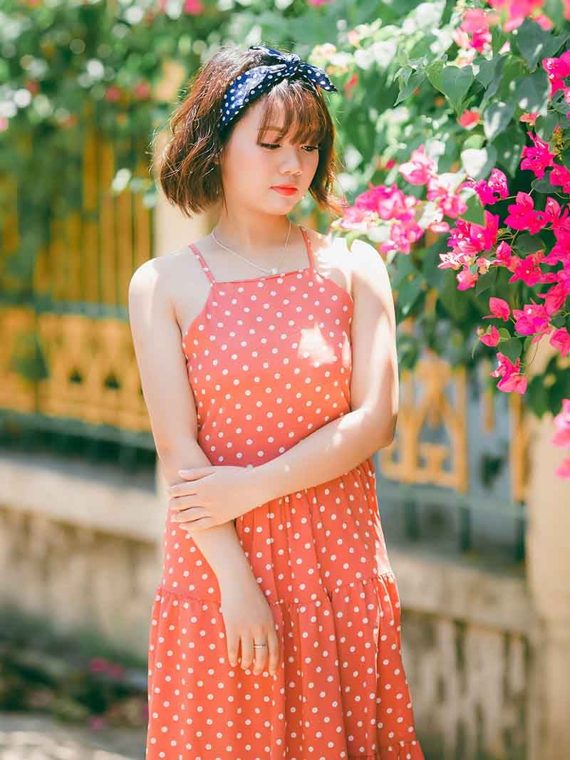 woman in orange polka dot spaghetti strap dress standing near flowers | easy sewing projects for beginners