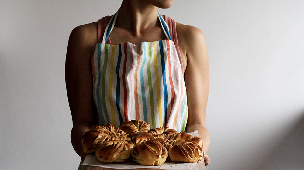 woman holding tray with breads | 20 Apron Pattern Projects to Get Crazy in the Kitchen With | Featured