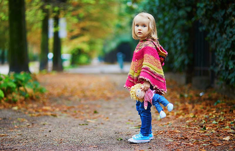 adorable toddler girl walking park on | knitted poncho