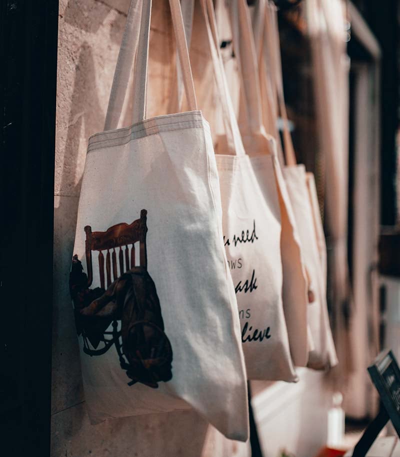 cloth tote bags with assorted prints hanging on a rack | easy sewing projects for beginners
