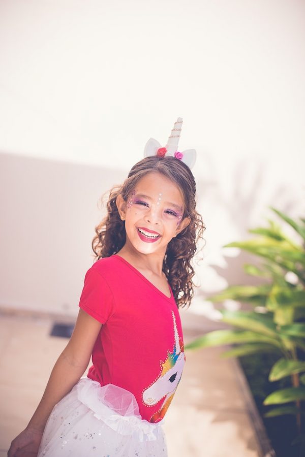 girl with curly hair wearing unicorn headband, unicorn tees and skater skirt | halloween costumes for girls