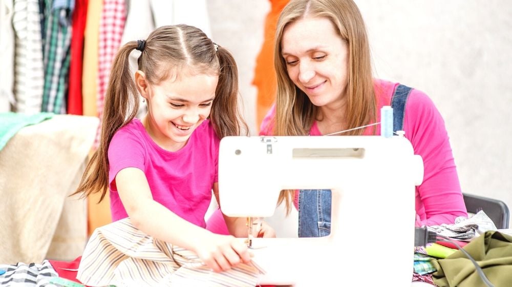 happy teacher teaches little girl sew | Fun Sewing Ideas For Moms and Kids | Featured