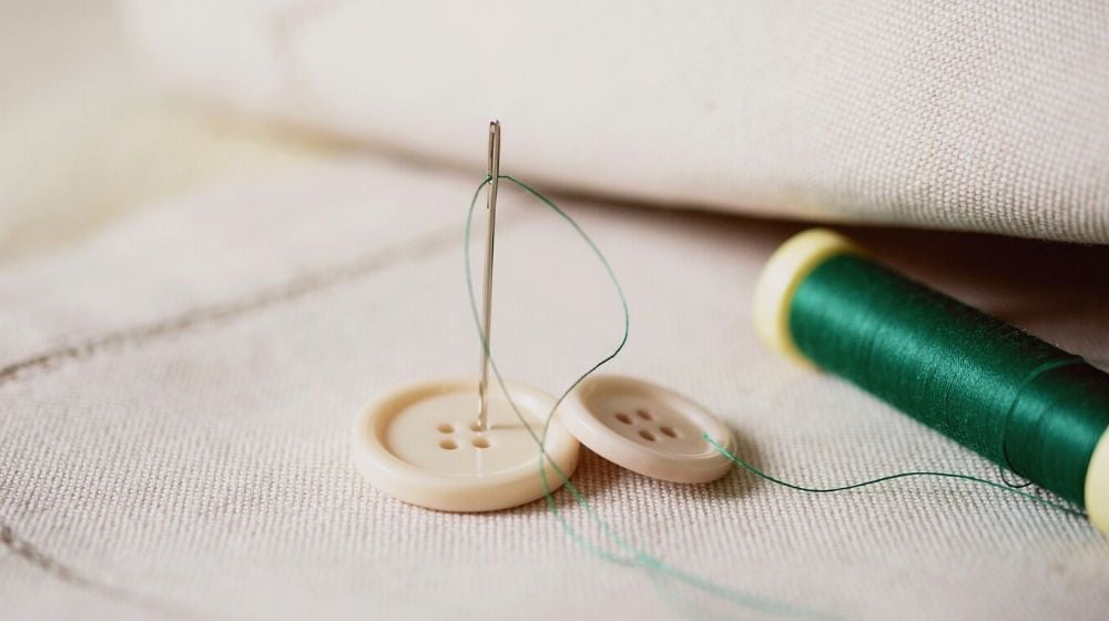 needles and button while tailoring fabric | How To Sew A Button Like An Expert
