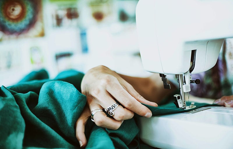 person sewing green textile using white electric sewing machine | basic sewing skills