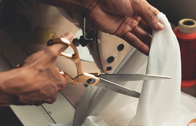 person cutting white cloth | sewing hacks