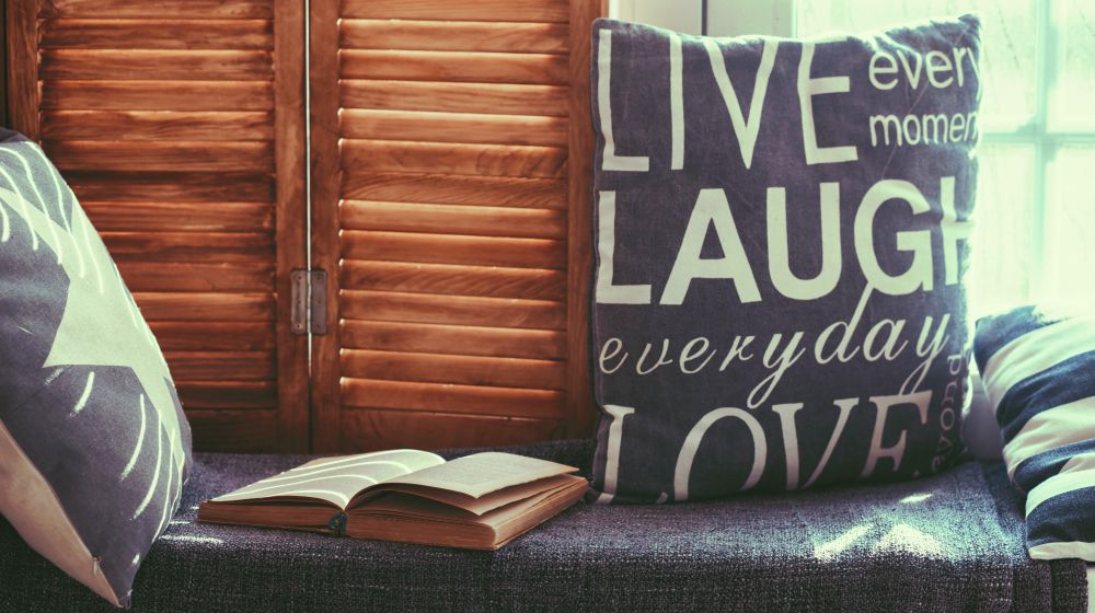 Warm and cozy window seat with cushions and a opened book | Nifty Home Decor Sewing Projects For Thrifty Home Makeovers | Featured